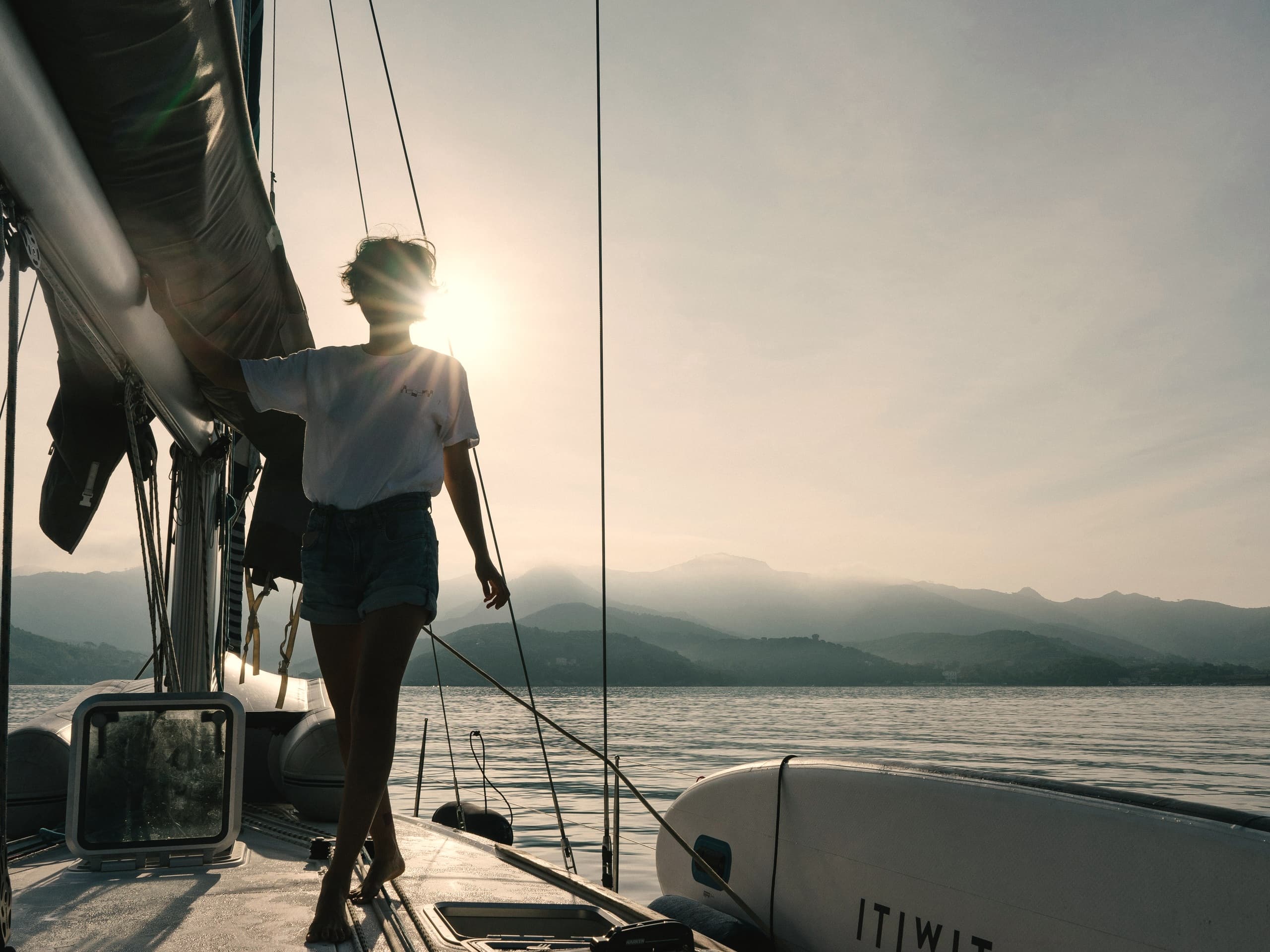 Person an Deck einer Segelyacht im Gegenlicht